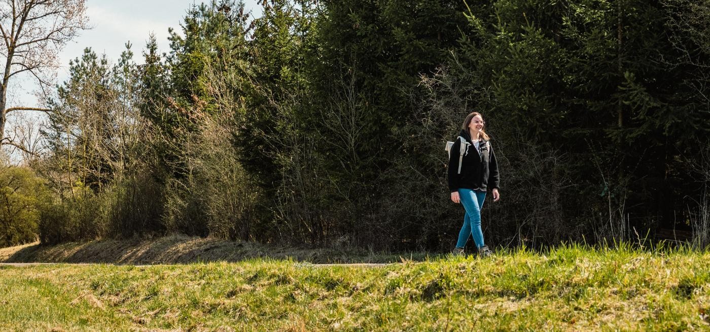 Frau wandert an einem Wald entlang
