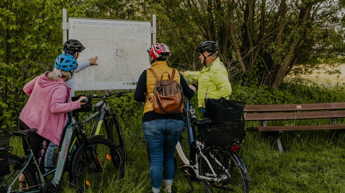 Vier Personen stehen mit ihren Fahrrädern vor einer Infotafel 