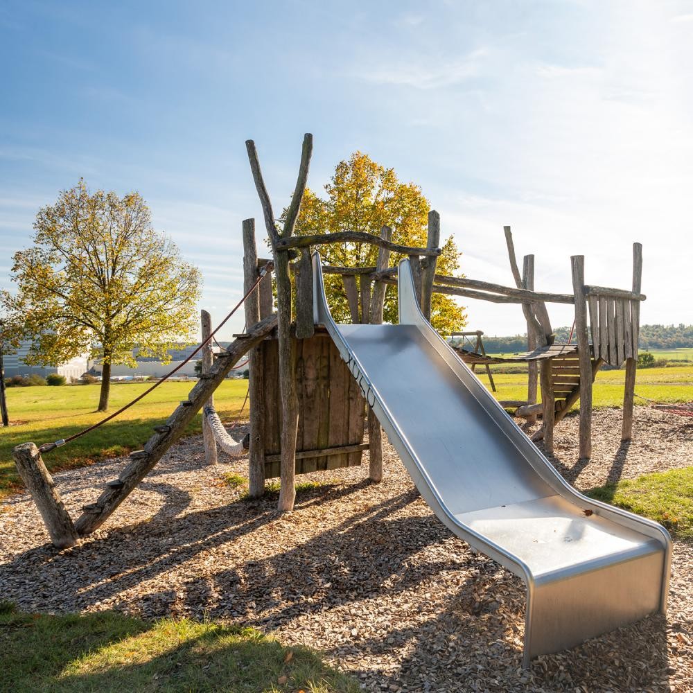 Spielplatz mit verschiedenen Spielgeräten, darunter eine Rutsche und ein Klettergerüst