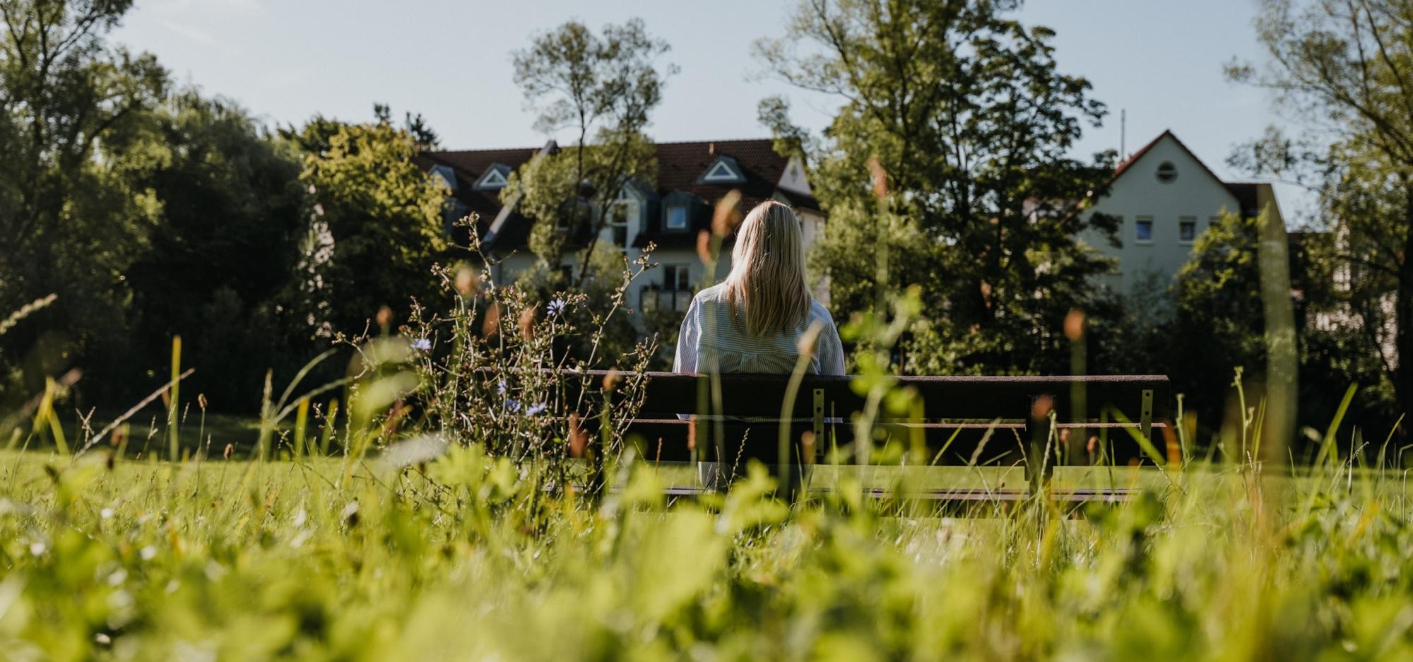 Frau sitzt auf einer Bank und blickt in die Ferne